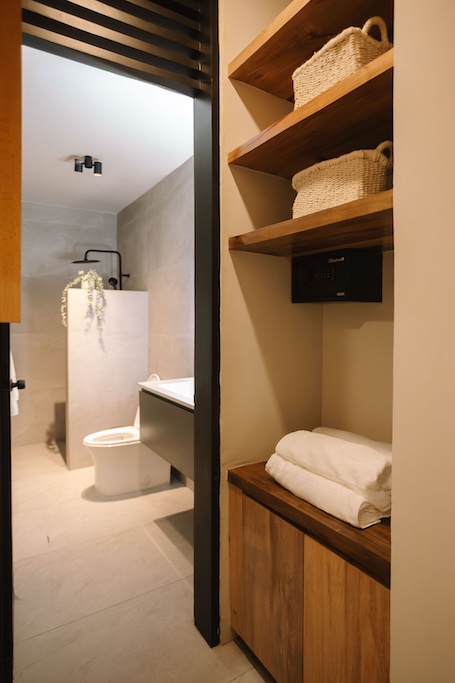 nicchia portaoggetti con ripiani in legno e asciugamani piegati accanto a un mobile che dà su un bagno moderno con cabina doccia e WC