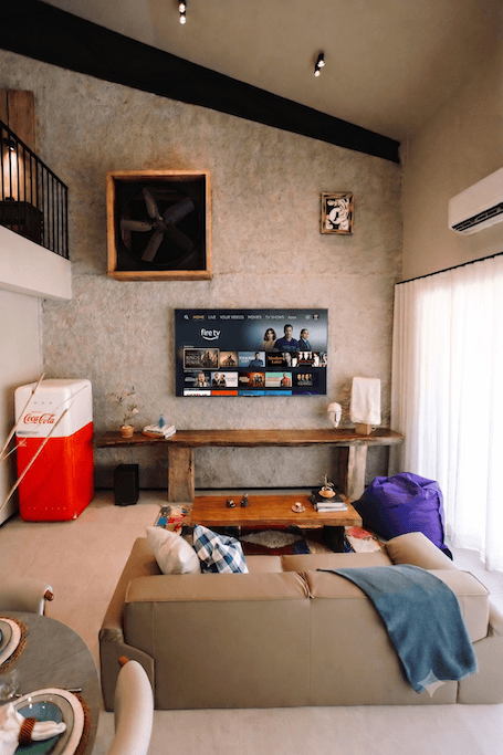 Coke room living room the hidden inn punta cana cozy living room with a wall mounted tv wooden console beige sectional sofa and a purple bean bag by the window a teal blanket draped over the sofa