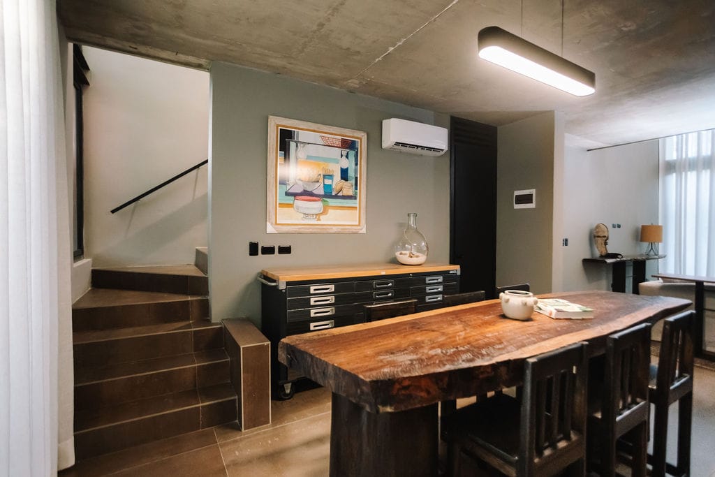 Private loft dining table the hidden inn punta cana rustic modern dining area with a long wooden table dark chairs and a storage credenza against a pale wall